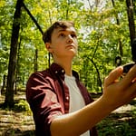 freelancer in woods searching with compass