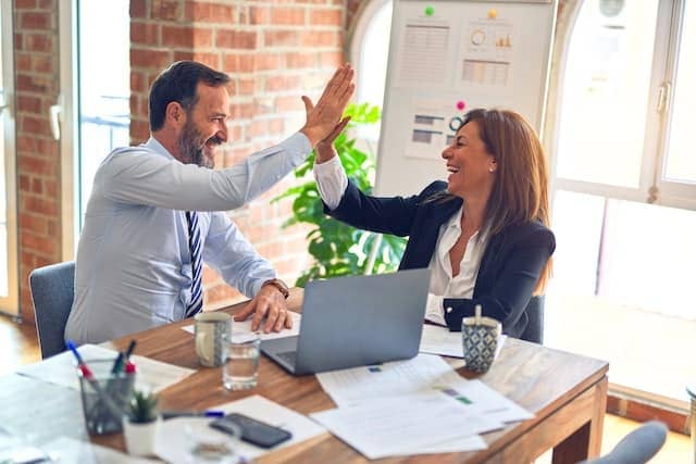 male manager with female coworker with laptop on desk